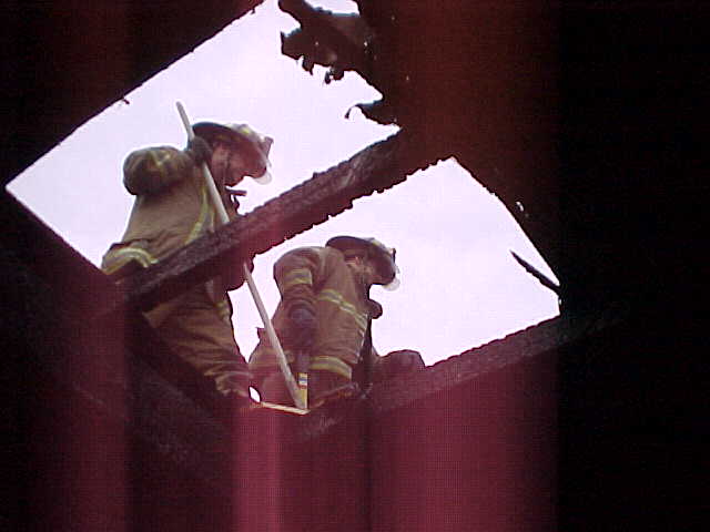 Firefighters seen from below through a roof ventilation opening